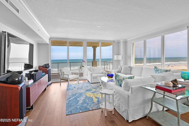 living area featuring a textured ceiling, crown molding, visible vents, hardwood / wood-style floors, and a water view