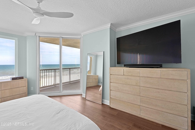 bedroom featuring a textured ceiling, a water view, access to exterior, ornamental molding, and wood finished floors