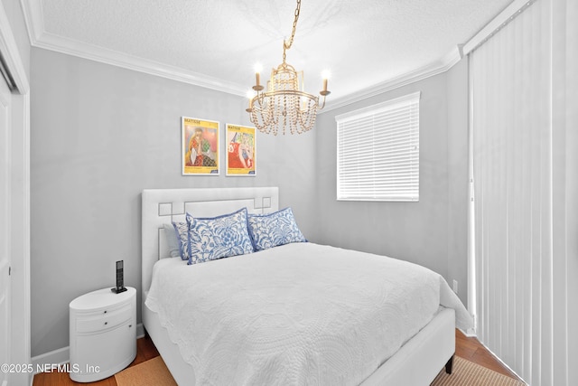 bedroom with a notable chandelier, crown molding, baseboards, a textured ceiling, and wood finished floors