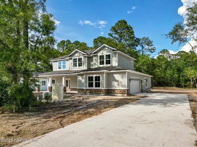 85084 Southern Creek Blvd, Fernandina Beach, FL 32034 - view of front of house with board and batten siding, a porch, driveway, and stone siding