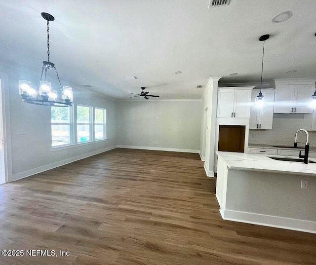 85084 Southern Creek Blvd, Fernandina Beach, FL 32034 - kitchen featuring baseboards, white cabinetry, a sink, ceiling fan with notable chandelier, and hanging light fixtures