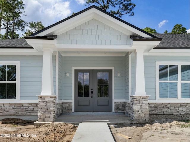85118 Southern Creek Blvd, Fernandina Beach, FL 32034 - view of exterior entry featuring covered porch, a shingled roof, french doors, and stone siding