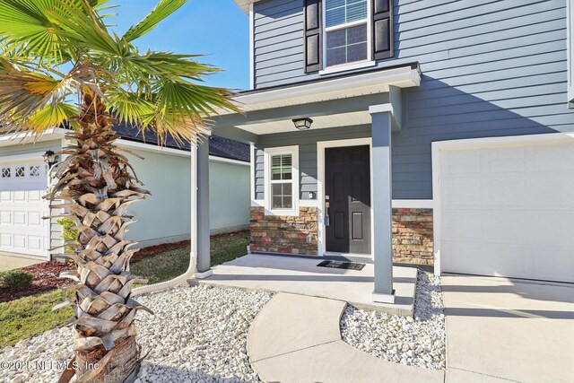 entrance to property featuring a garage, stone siding, and covered porch