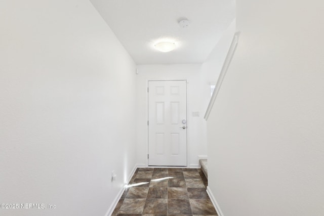 doorway with stone finish flooring and baseboards