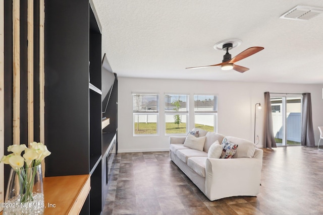 living area featuring a ceiling fan, visible vents, and a textured ceiling