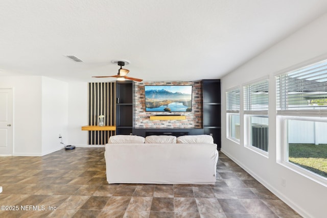 living area with a wealth of natural light, visible vents, baseboards, and a ceiling fan