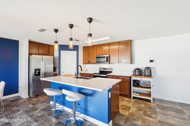 kitchen with visible vents, a sink, light countertops, appliances with stainless steel finishes, and a kitchen island with sink