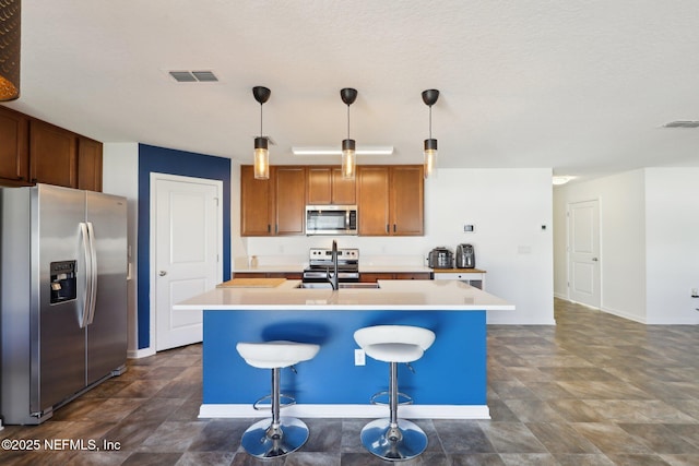 kitchen with light countertops, a center island with sink, visible vents, and stainless steel appliances