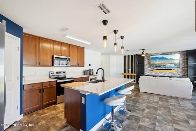 kitchen with visible vents, a sink, stainless steel appliances, light countertops, and brown cabinets