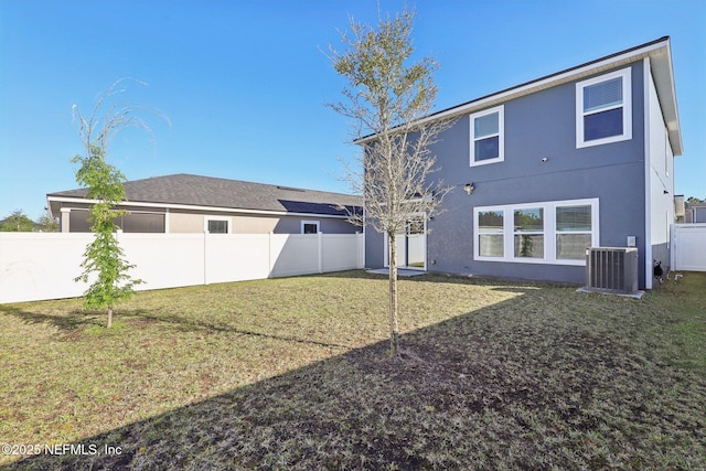 back of property with central air condition unit, a lawn, a fenced backyard, and stucco siding