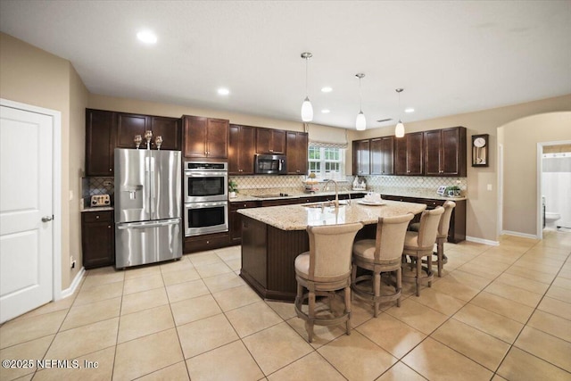 1074 Spanish Bay Ct, Orange Park, FL 32065 - kitchen featuring light tile patterned flooring, a sink, arched walkways, and appliances with stainless steel finishes