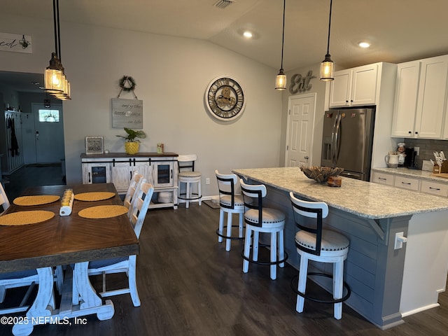665 Flach Dr, Saint Johns, FL 32259 - kitchen with stainless steel refrigerator with ice dispenser, white cabinetry, a kitchen island, light stone counters, and dark wood-type flooring