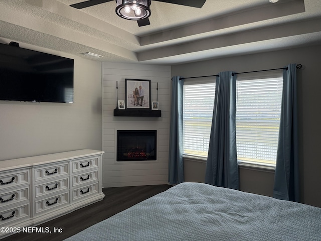 665 Flach Dr, Saint Johns, FL 32259 - bedroom featuring dark wood-style flooring, a large fireplace, a ceiling fan, and a raised ceiling