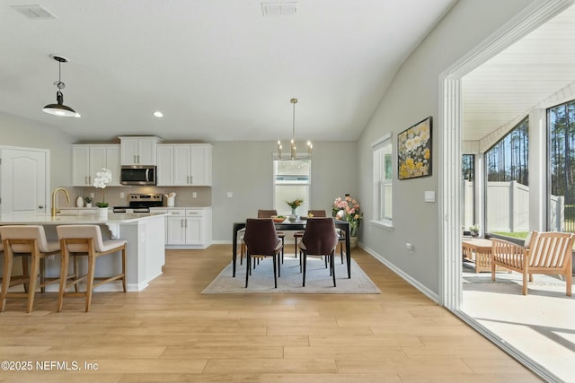 dining area with visible vents, light wood-type flooring, and lofted ceiling