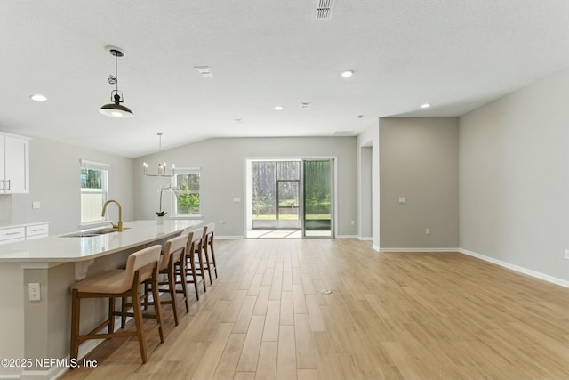 kitchen with visible vents, light countertops, light wood-style flooring, white cabinets, and a sink