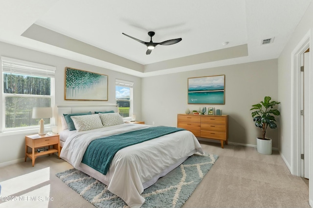 bedroom featuring visible vents, a raised ceiling, baseboards, and a ceiling fan
