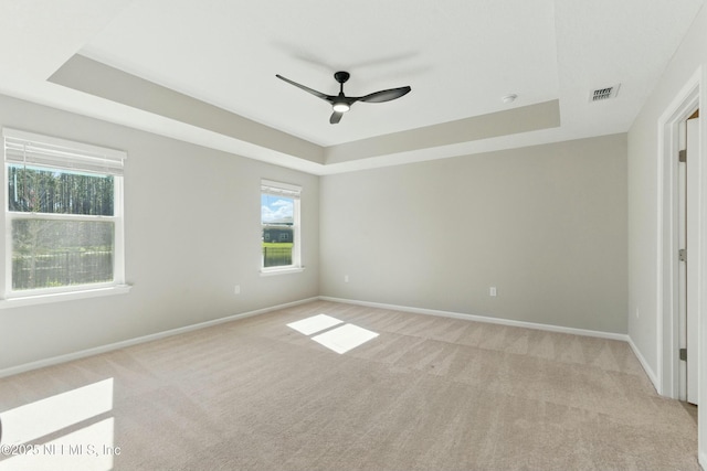 spare room with visible vents, a raised ceiling, and baseboards