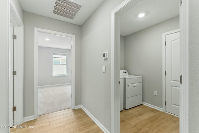 laundry area featuring visible vents, light wood finished floors, baseboards, washer / dryer, and laundry area