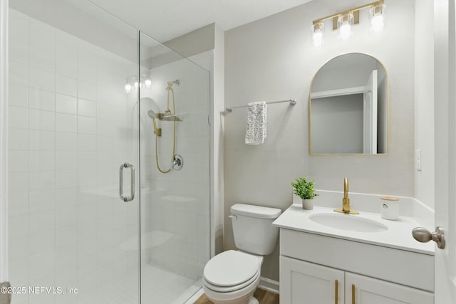full bath with vanity, a shower stall, and toilet