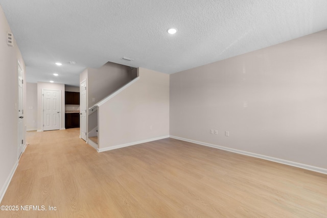 interior space featuring recessed lighting, baseboards, a textured ceiling, and light wood finished floors