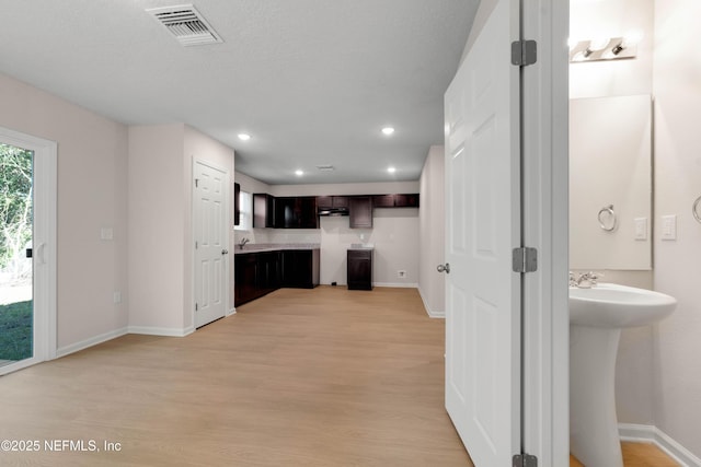 kitchen featuring visible vents, baseboards, dark brown cabinetry, and light wood finished floors