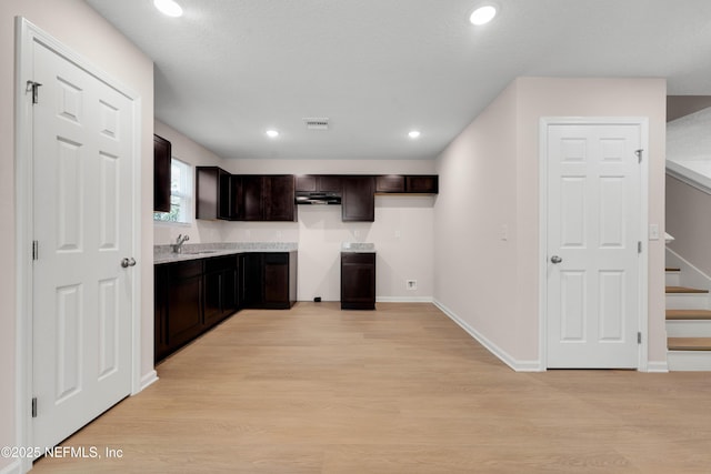 kitchen with a sink, recessed lighting, light wood-style floors, baseboards, and dark brown cabinets