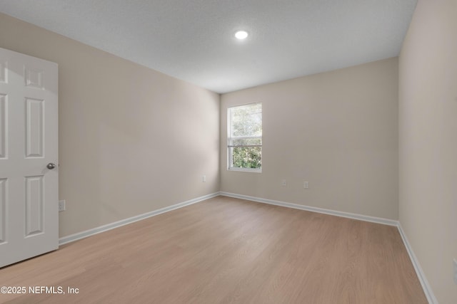 unfurnished room with light wood-style flooring and baseboards