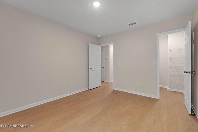 unfurnished bedroom with visible vents, baseboards, a spacious closet, and light wood finished floors