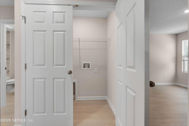laundry room featuring washer hookup, laundry area, light wood-style floors, and baseboards