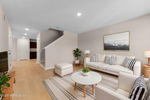 living area featuring recessed lighting, light wood-style floors, visible vents, and a textured ceiling