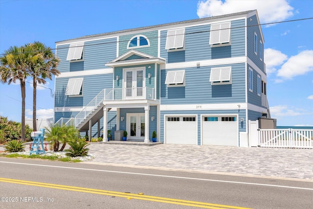 beach home with stairway, fence, an attached garage, french doors, and decorative driveway