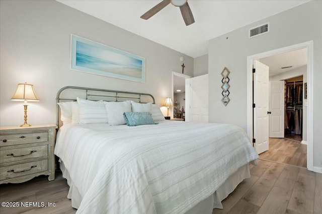 bedroom with baseboards, ceiling fan, visible vents, and wood finished floors