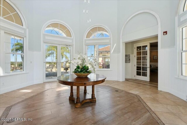 foyer featuring baseboards, wood finished floors, a decorative wall, and french doors