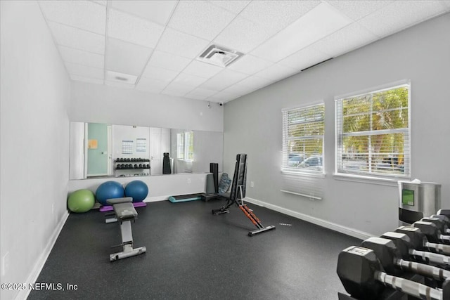 exercise room with baseboards, visible vents, and a paneled ceiling