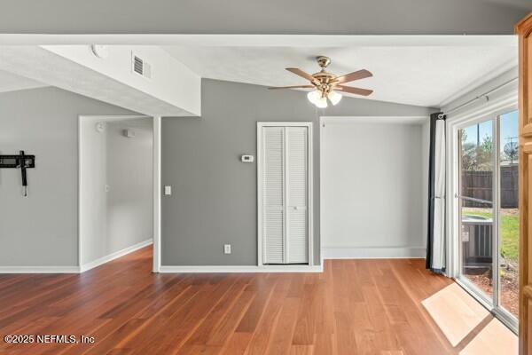 empty room featuring wood finished floors, a ceiling fan, baseboards, visible vents, and lofted ceiling