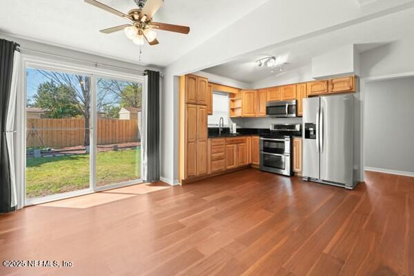 kitchen featuring dark countertops, dark wood-type flooring, lofted ceiling, appliances with stainless steel finishes, and a sink