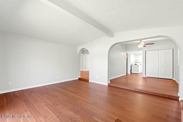 empty room with arched walkways, baseboards, ceiling fan, and wood finished floors