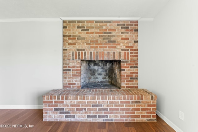 interior details featuring crown molding, a brick fireplace, wood finished floors, and baseboards