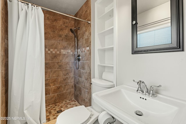 bathroom featuring a sink, toilet, a stall shower, and a textured ceiling