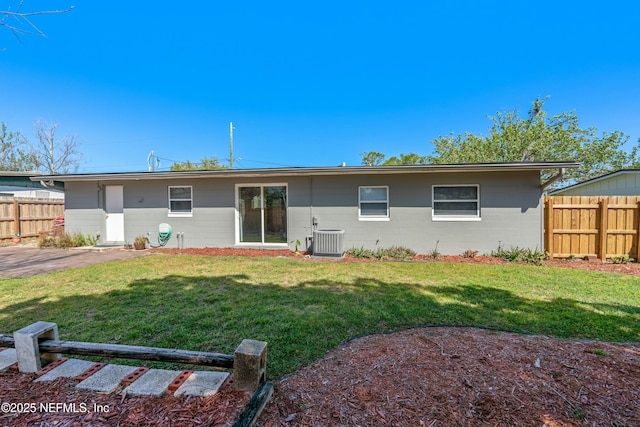 rear view of property featuring cooling unit, a yard, concrete block siding, and fence