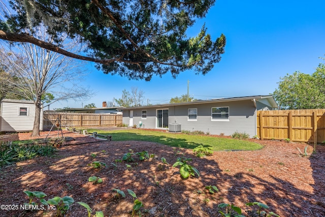 back of house featuring an outbuilding, a lawn, cooling unit, and a fenced backyard