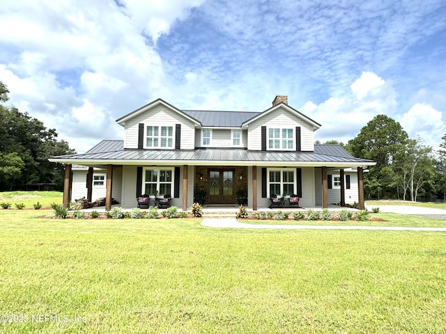 country-style home featuring a standing seam roof, a porch, a front lawn, and metal roof