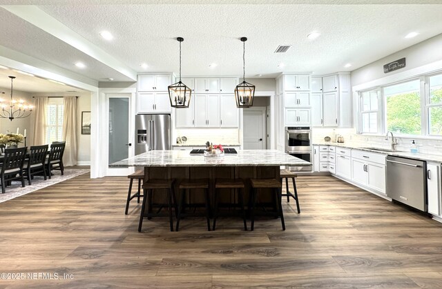 kitchen featuring dark wood-style floors, visible vents, an inviting chandelier, a sink, and appliances with stainless steel finishes