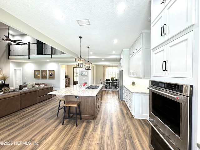 kitchen featuring stainless steel appliances, a kitchen bar, visible vents, and white cabinets