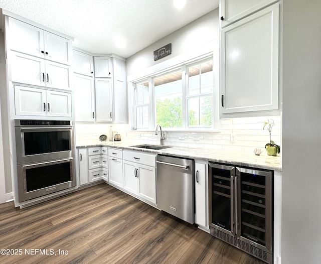 kitchen with white cabinetry, beverage cooler, appliances with stainless steel finishes, and a sink