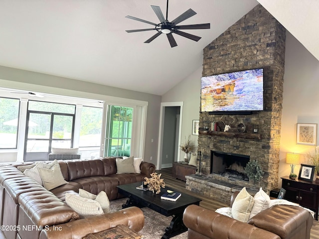 living area with baseboards, ceiling fan, a fireplace, wood finished floors, and high vaulted ceiling