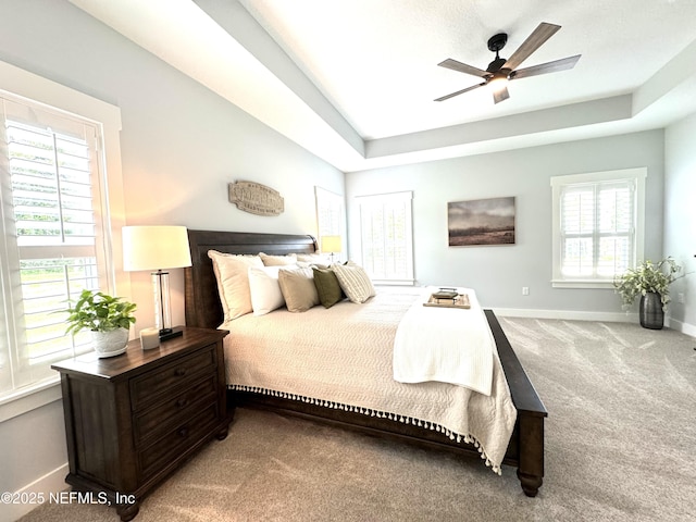 bedroom featuring ceiling fan, a raised ceiling, baseboards, and carpet floors