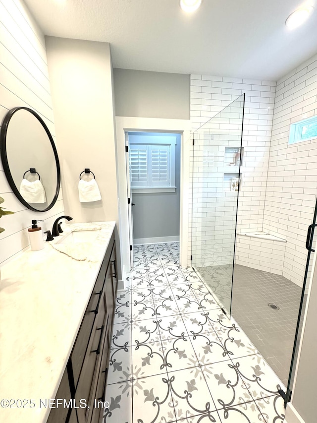 full bath featuring baseboards, vanity, and a shower stall
