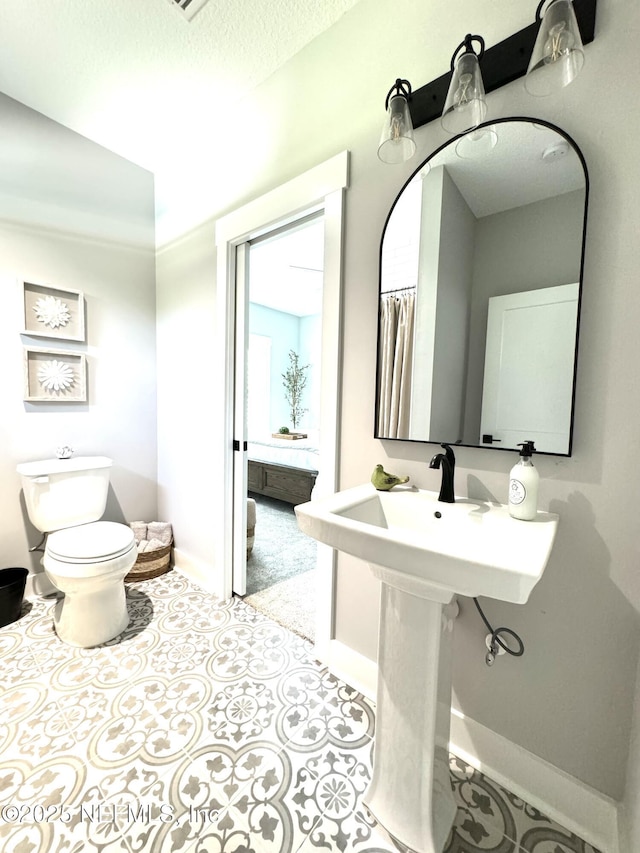 bathroom featuring tile patterned floors, toilet, baseboards, and a textured ceiling