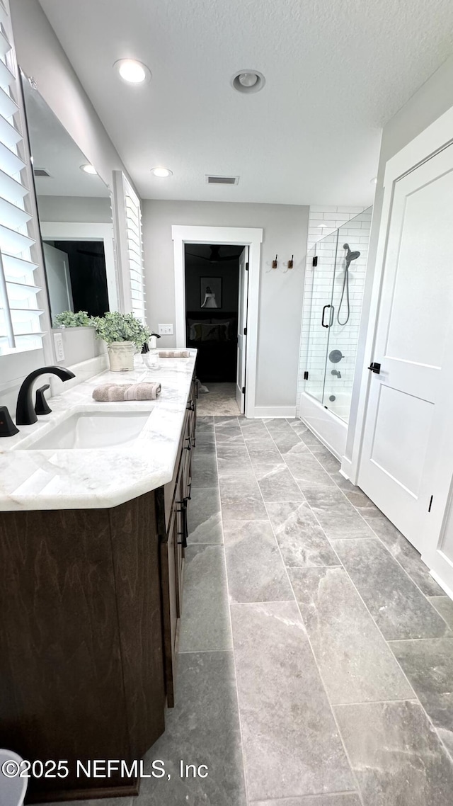 full bath featuring visible vents, double vanity, recessed lighting, a sink, and a textured ceiling